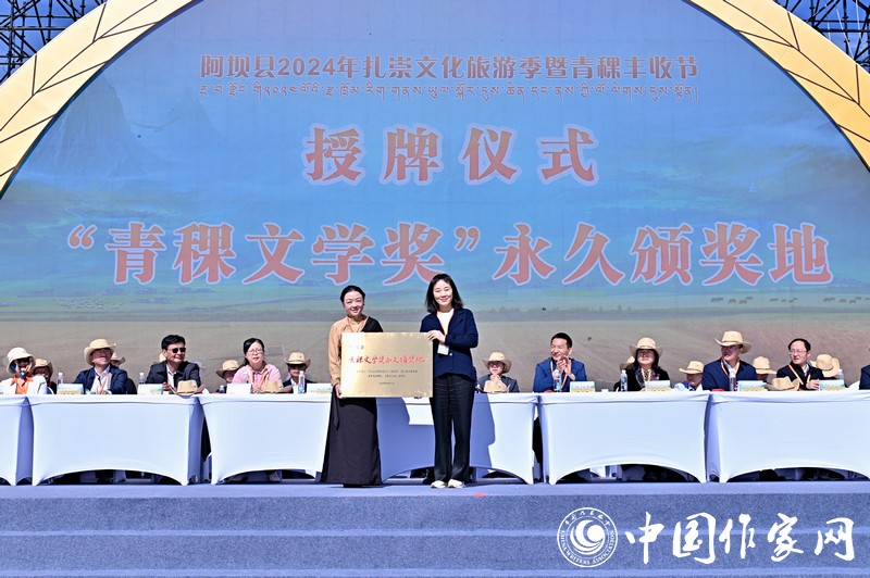 陳亞軍主編代表《民族文學(xué)》向阿壩縣授牌，紅梅部長接牌。